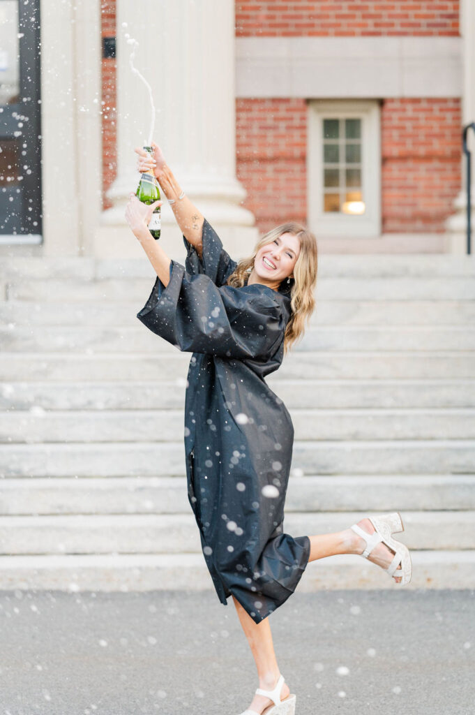 College grad in cap and gown doing a champagne spray