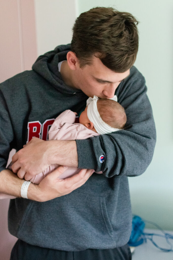New dad kissing newborn baby girl's head in Boston, MA