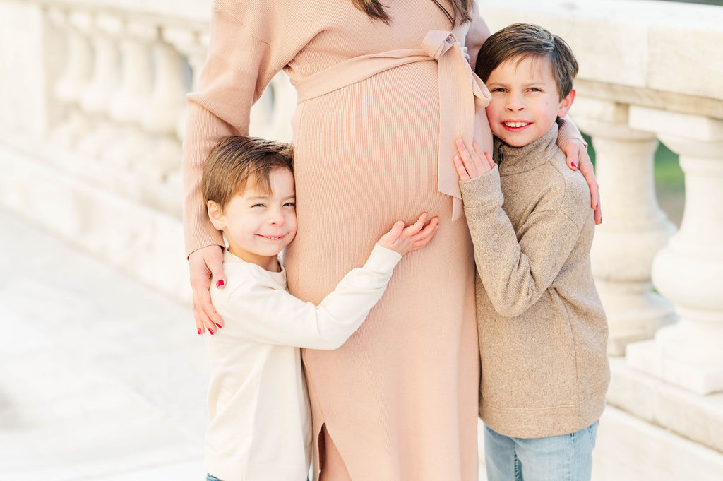 Pregnant mom with boys hugging her bump