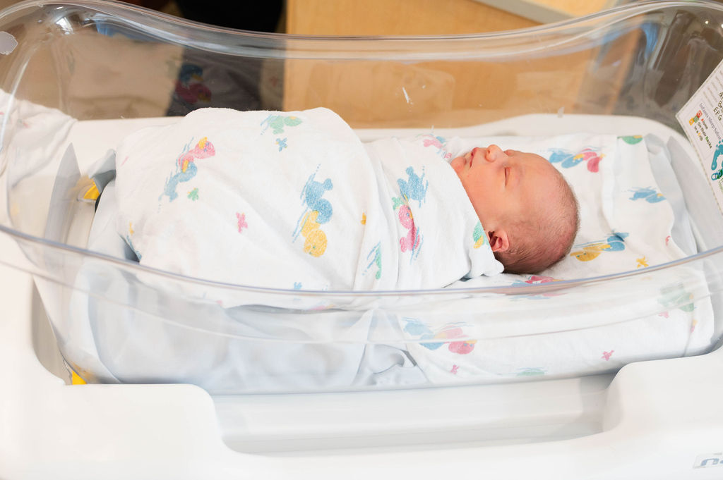 baby wrapped in swaddle in bassinet in hospital