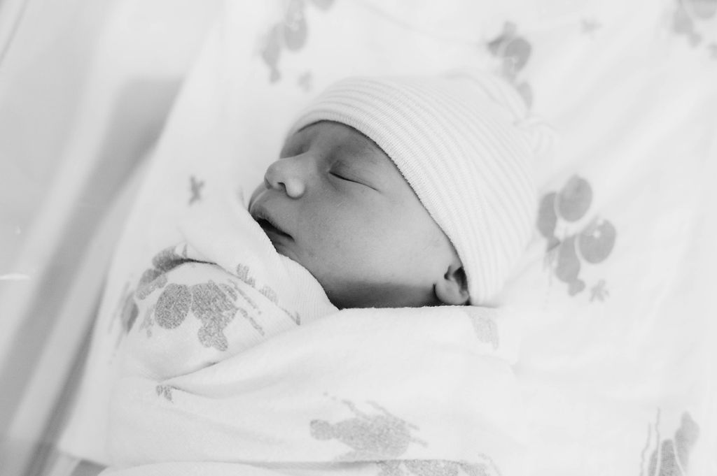 Newborn baby wrapped in a swaddle in the hospital bassinet
