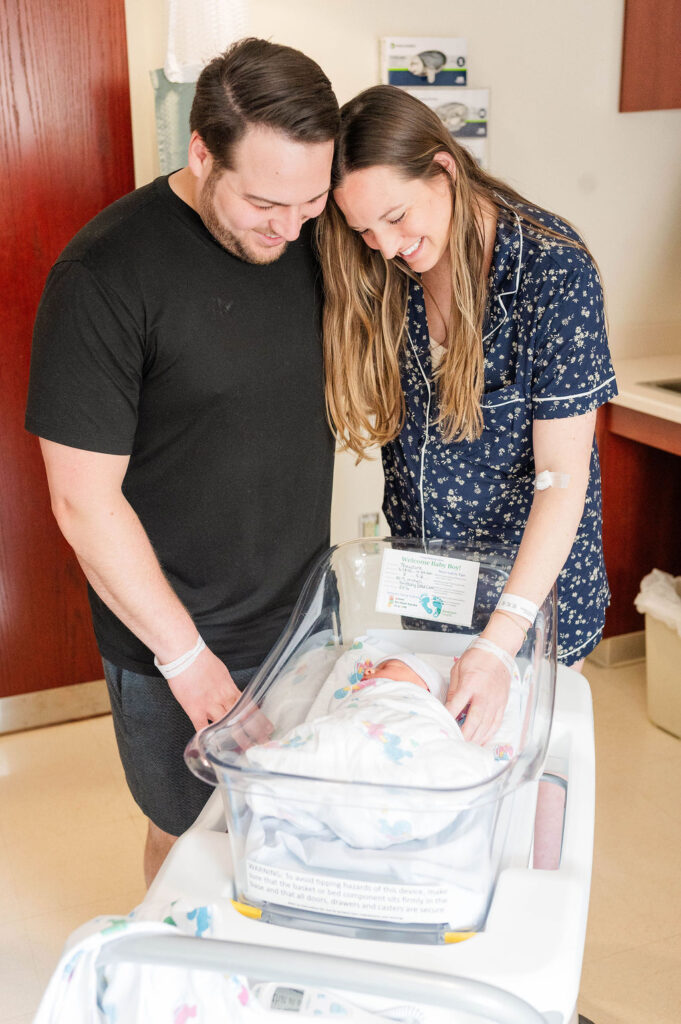 New mom and dad look at their newborn in the hospital bassinet at the Clough Birthing Center