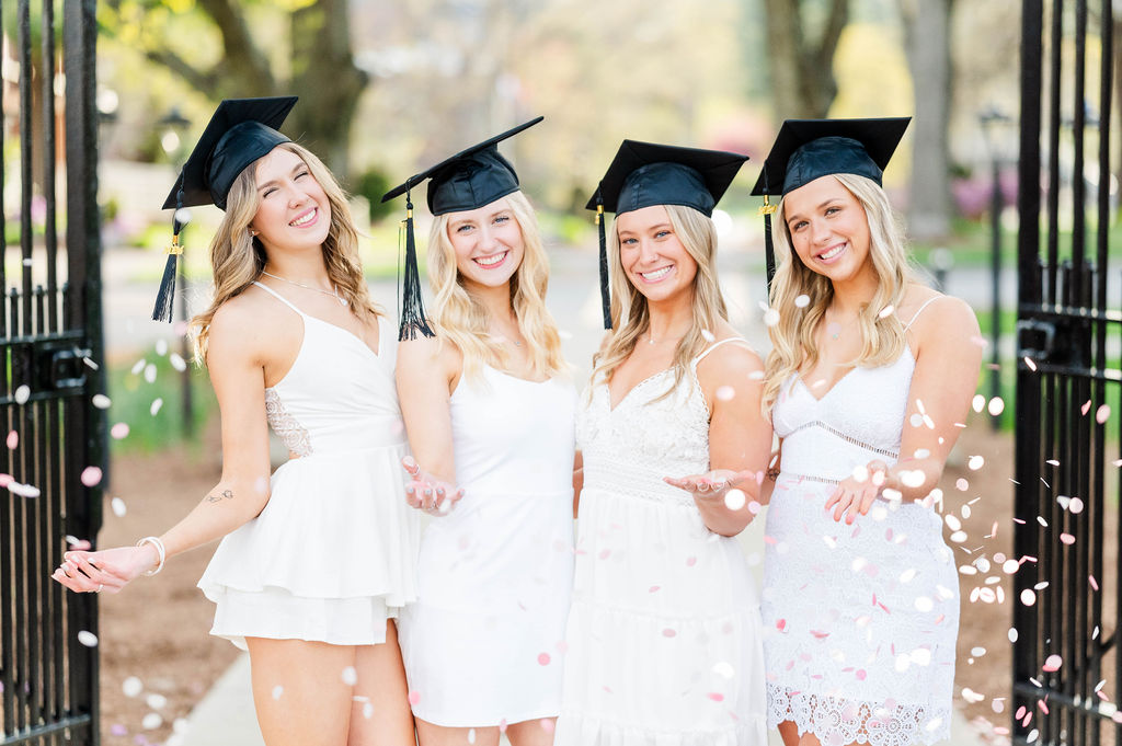 Four college grad girls with caps with confetti