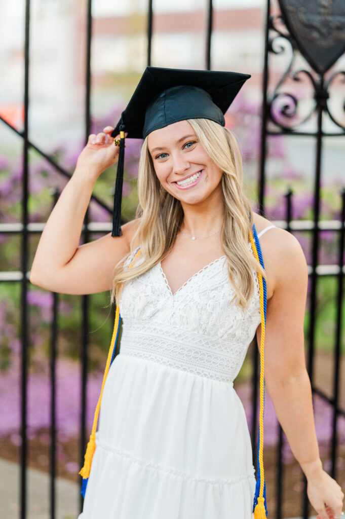 College grad with cap on holding it and smiling