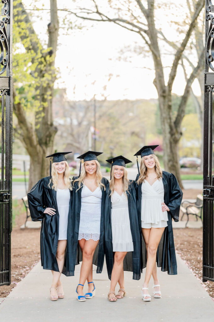 Four college grads in cap and gown at Worcester State University