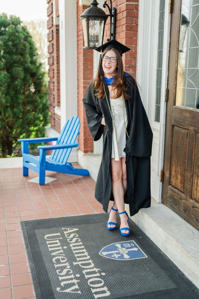 College grad standing on Assumption University mat in cap and gown