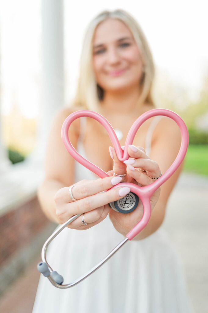 College grad holding her stethoscope in the shape of a heart