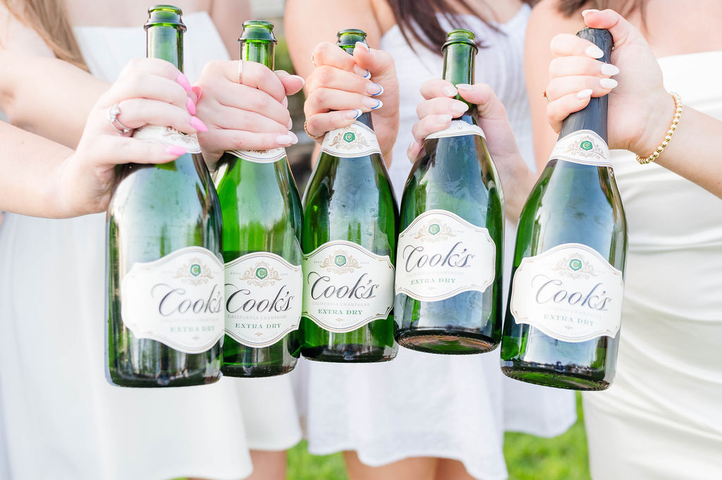 Group of hands holding champagne bottles to celebrate Worcester College graduation