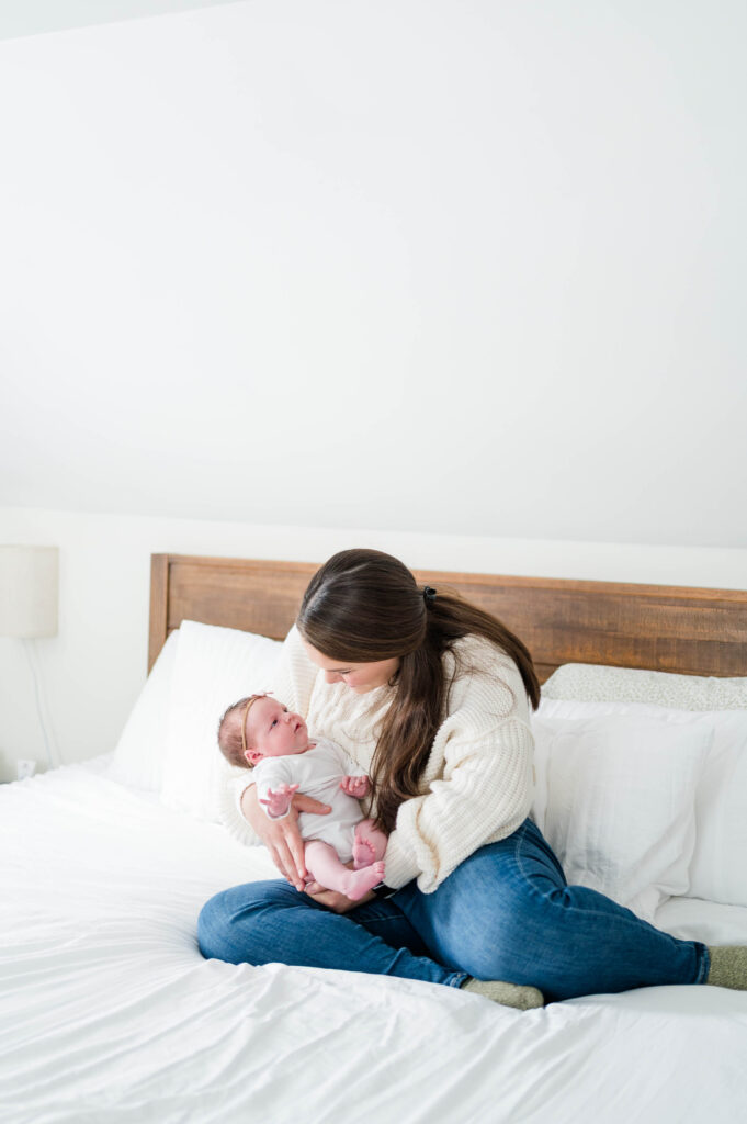 mom and newborn baby looking at each other on bed