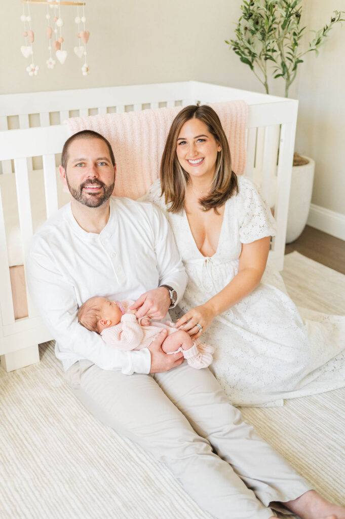 Mom and dad in front of crib with newborn baby