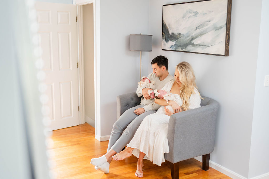 Cambridge newborn photographer's image of mom and dad on couch with newborn twins