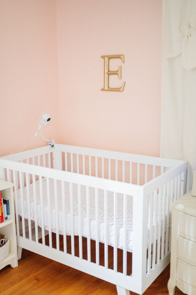 Rhode Island newborn photographer shot of white crib in pink room with a gold E above it on the wall