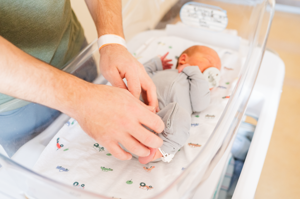 Image of baby with dad starting to change his clothes taken by best Boston newborn photographer
