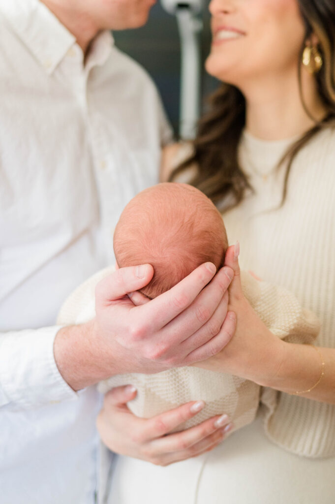 Baby in mom and dad's arms while mom and dad look at each other