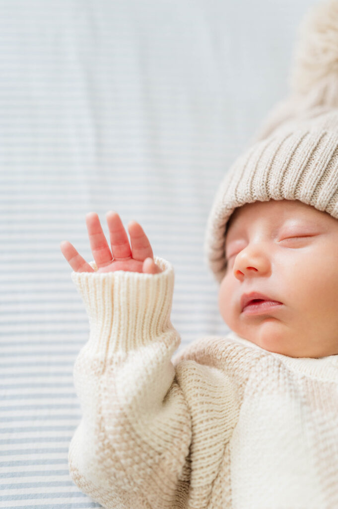 Newborn baby sleeping in crib with little hand