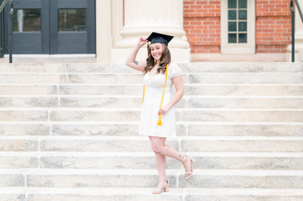 Grad in white dress standing on stairs