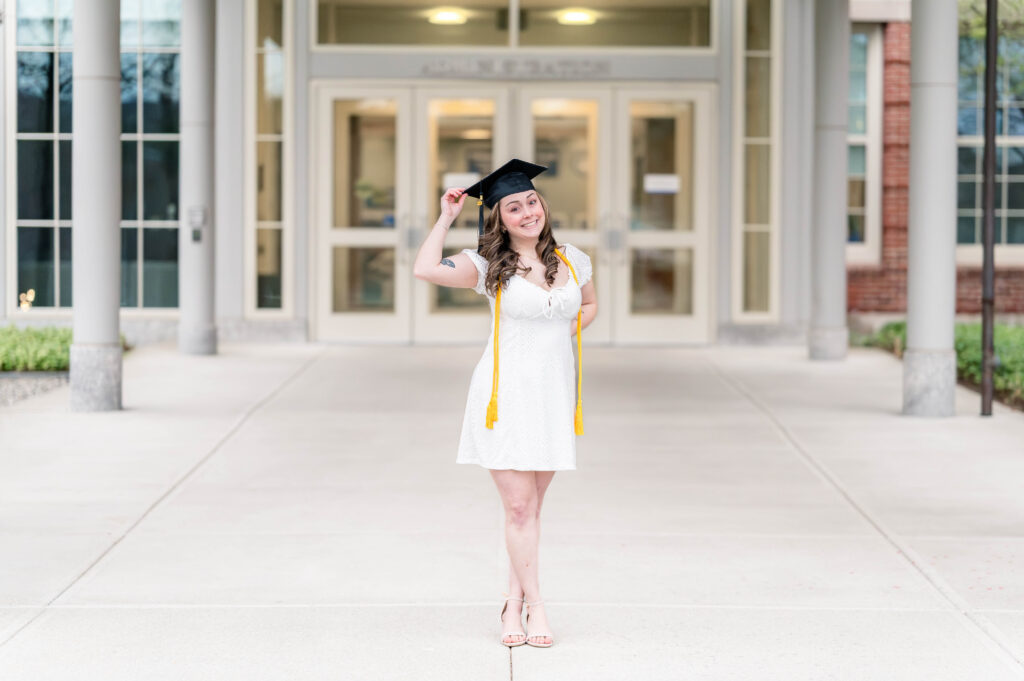 Grad wearing cap and cords and white dress