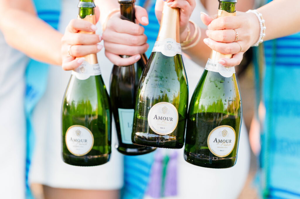 Grads holding up champagne bottles