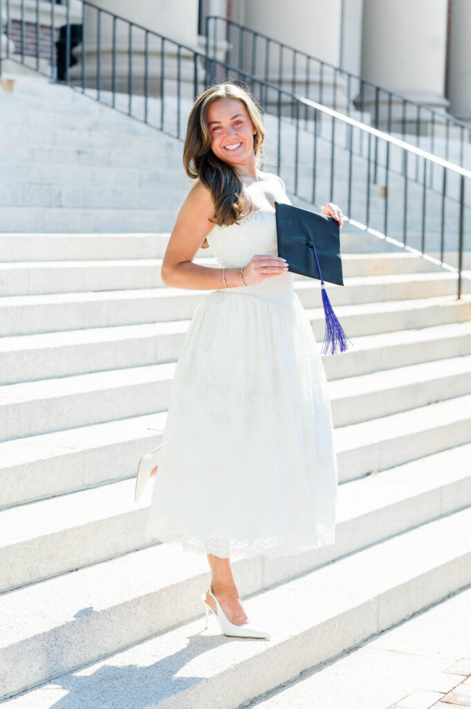 College of the Holy Cross grad photographer image of grad holding cap on stairs