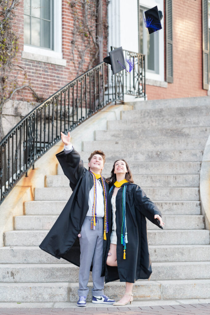 Couple throwing caps in the air together at group grad session at the College of the Holy Cross