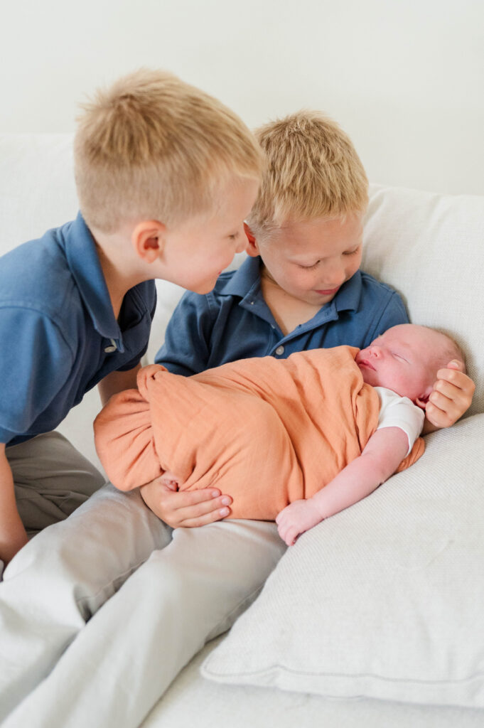 Needham MA newborn lifestyle photographer image of boys looking at baby sister